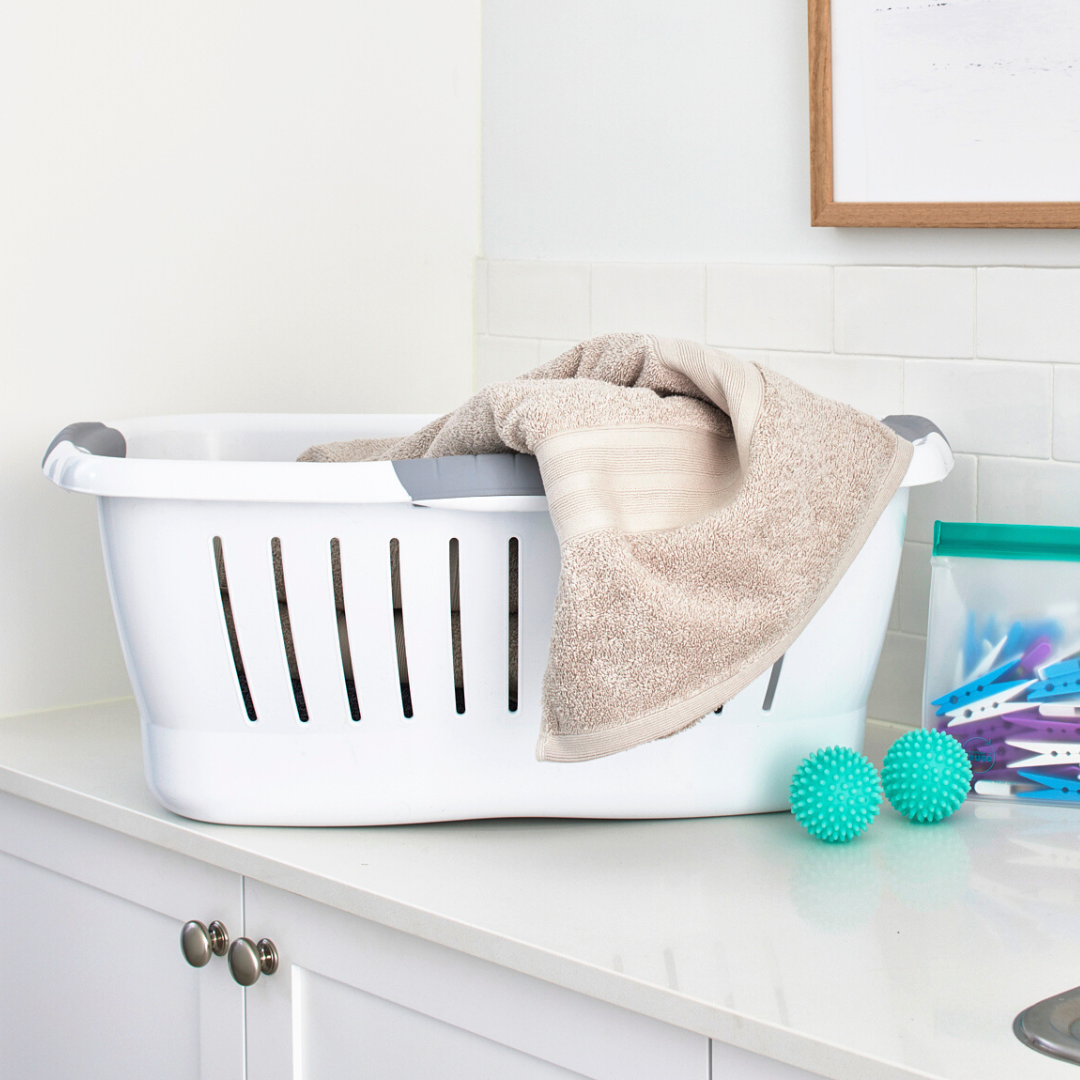 White plastic laundry basket sitting on top of washing machine in laundry